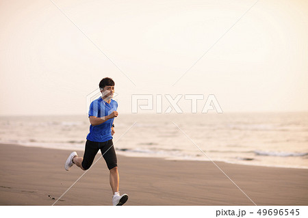 young Man running on  beach at sunset 49696545