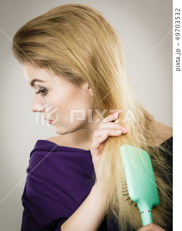 Woman brushing her long hair with brush Woman brushing her long hair with brush 49703532