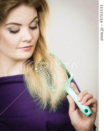 Woman brushing her long hair with brush Woman brushing her long hair with brush 49703533