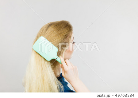 Woman brushing her long hair with brush Woman brushing her long hair with brush 49703534