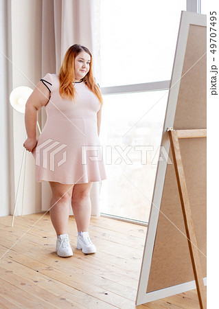 Nice plump woman trying on a new dress Nice plump woman trying on a new dress 49707495