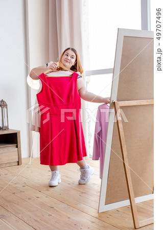 Positive nice woman holding a pink dress Positive nice woman holding a pink dress 49707496