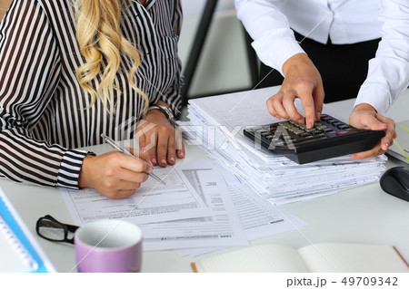 Two female accountants counting on calculator Two female accountants counting on calculator 49709342