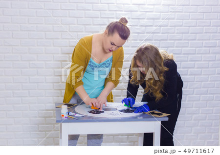 Women decorators, designers painting wooden circle decoration Women decorators, designers painting wooden circle decoration 49711617