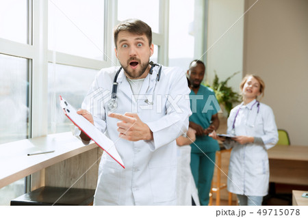 Beautiful surprised doctor over hospital background Beautiful surprised doctor over hospital background 49715078