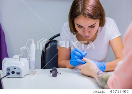 Professional beautician applying nail polish to female nail Professional beautician applying nail polish to female nail 49715406