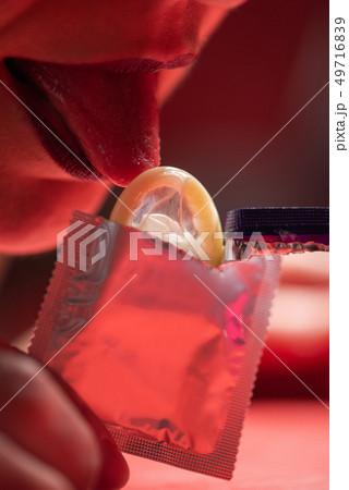 Female tongue and open condom in red light Female tongue and open condom in red light 49716839