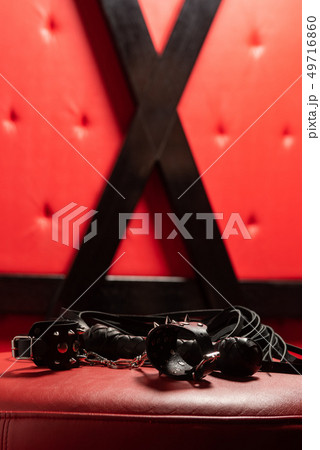 Sexy black leather toys on red sofa. 49716860