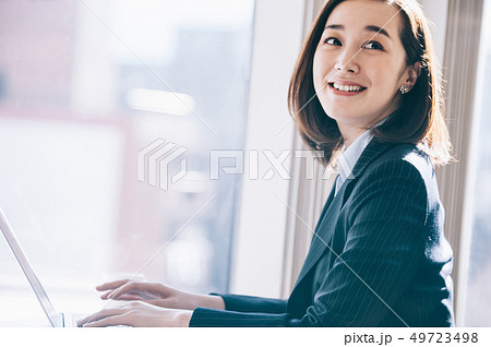 窓際の席でパソコンに向かう上司の女性 49723498