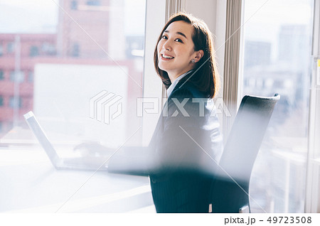 窓際の席でパソコンに向かう上司の女性 49723508