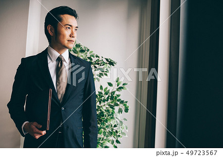 窓際でファイルを抱えて立つ上司の男性 窓際でファイルを抱えて立つ上司の男性 49723567