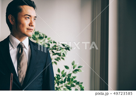 窓際でファイルを抱えて立つ上司の男性 窓際でファイルを抱えて立つ上司の男性 49723585