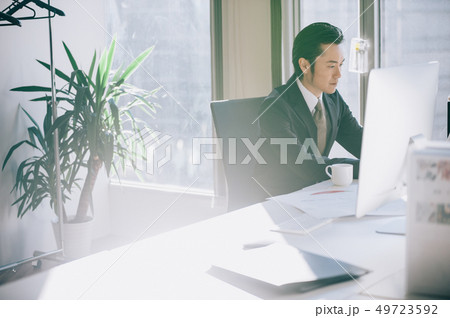 窓際の席でパソコンに向かう上司の男性 49723592