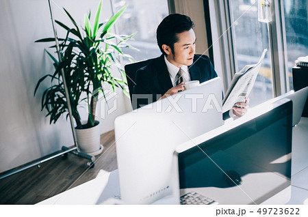 コーヒーカップを手に新聞を読む上司の男性 49723622