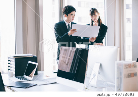 互いの資料を見比べる新入社員の男性と女性 49723693