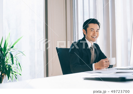 窓際の席でコーヒーを飲む上司の男性 49723700