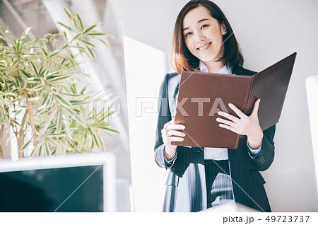 オフィスで柱にもたれファイルを確認する女性 49723737