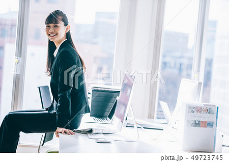 オフィスでデスクに腰掛ける新入社員の女性 49723745