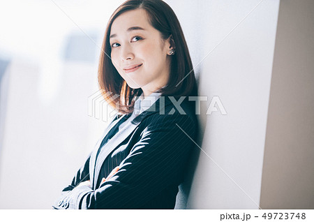 オフィスで柱にもたれ微笑む女性 49723748