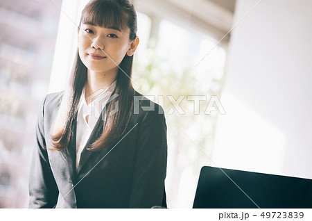 オフィスでデスクに腰掛ける新入社員の女性 49723839