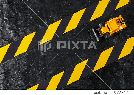 Yellow toy bulldozer on a black background Yellow toy bulldozer on a black background 49727476