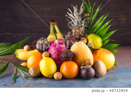 Assortment of exotic fruits with palm leaves on dark background Assortment of exotic fruits with palm leaves on dark background 49732859
