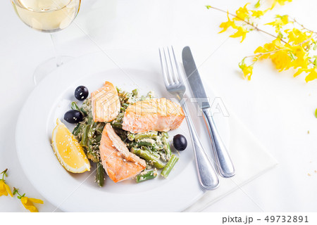 Grilled salmon with steamed green beans and lemon on white background with white wine Grilled salmon with steamed green beans and lemon on white background with white wine 49732891
