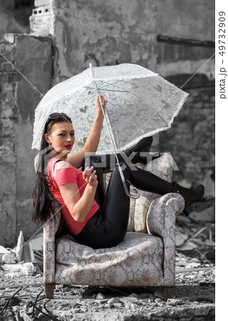 Pretty girl with umbrella sitting in chair 49732909