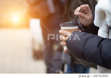 Close up hand in coat holding take away hot coffee 49732945