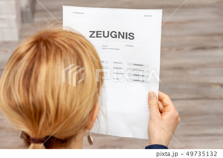 Mother holding a very bad German school certificate in her hands Translation: certificate day of 49735132