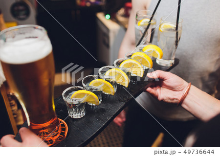 Male hands cheer with glasses of shot or liqueur. Friends drink shot or liqueur and cheers. Male Male hands cheer with glasses of shot or liqueur. Friends drink shot or liqueur and cheers. Male 49736644