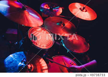 Drummer playing drum set at concert on stage. Music show. Bright scene lighting in club,drum sticks 49736733