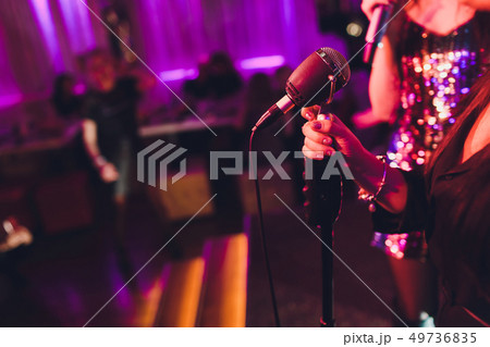 Girl in long gown performing on stage. Girl singing on the stage in front of the lights. Silhouette Girl in long gown performing on stage. Girl singing on the stage in front of the lights. Silhouette 49736835