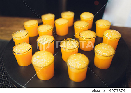 17 alcoholic drink in shot glasses with orange slices in the wood table. 49738744