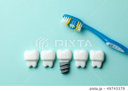 Healthy white teeth and implants on green mint background with toothbrush 49743379