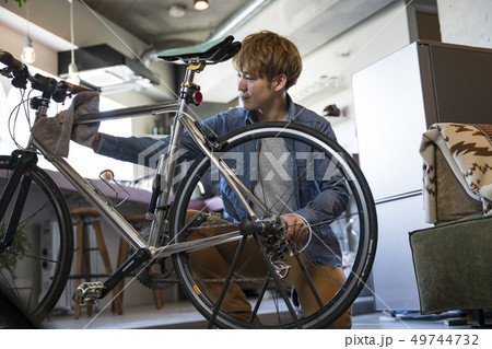 リビングで自転車の整備をする男性 49744732