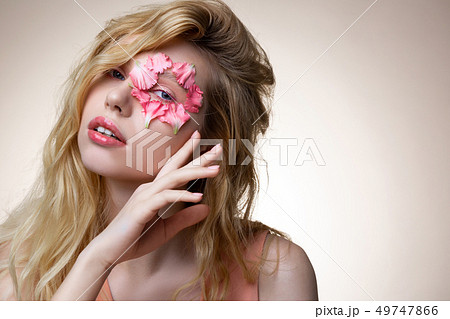 Model with pink lip gloss posing with pink petals on face Model with pink lip gloss posing with pink petals on face 49747866