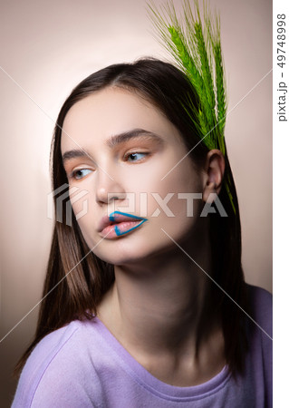 Appealing woman with blue lines on lips and green spikelet in hair 49748998