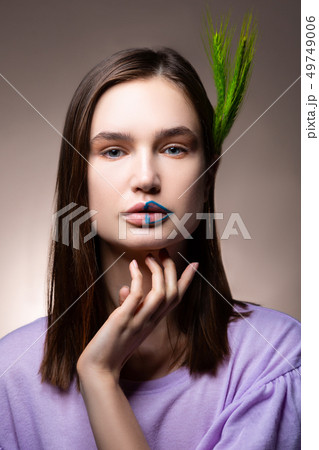 Blue-eyed model with blue lines on her lips posing with spikelet Blue-eyed model with blue lines on her lips posing with spikelet 49749006