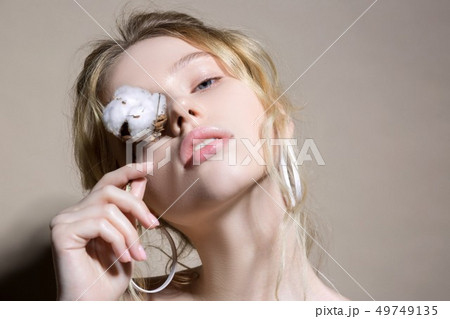 Appealing woman holding cotton standing near light wall 49749135