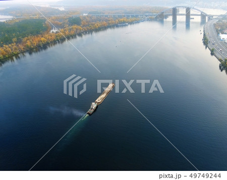 Scenic aerial cityscape of Kiev and river Dnipro at sunset. Tugboat supporting barge with sand bulk 49749244