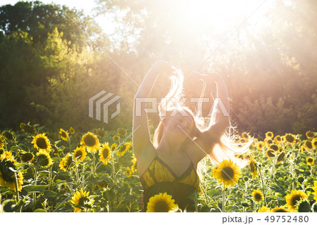 Beauty sunlit woman on yellow sunflower field Freedom and happiness concept 49752480