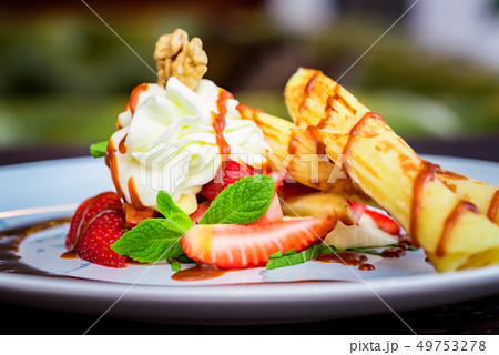 Close up delicious dessert with waffle rolls, ice cream and strawberries Close up delicious dessert with waffle rolls, ice cream and strawberries 49753278