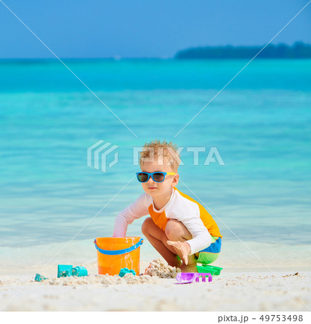 Three year old toddler playing on beach Three year old toddler playing on beach 49753498