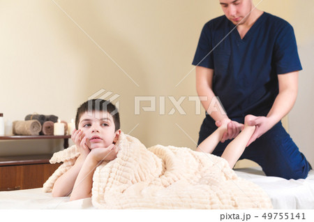 Little bored boy patient at reception at a professional masseuse. Foot Massage Therapy Little bored boy patient at reception at a professional masseuse. Foot Massage Therapy 49755141