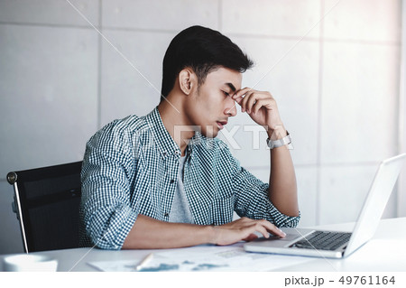 Tired and Stress Young Businessman Sitting on Desk 49761164