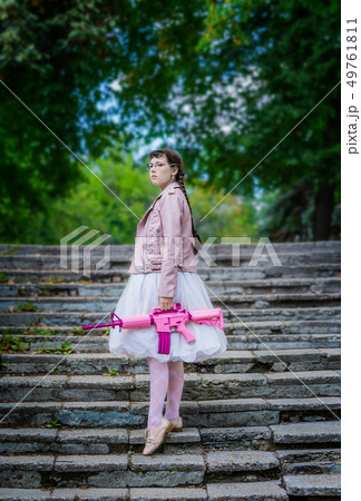 Woman with a pink rifle climbs the stairs up. 49761811