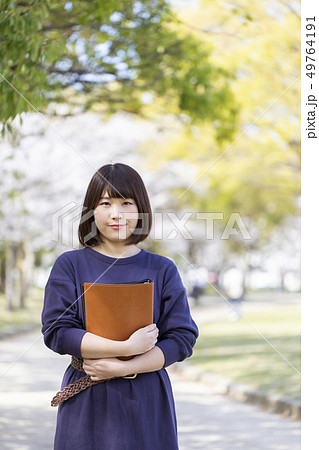 春の公園で書類を抱きかかえる学生 49764191