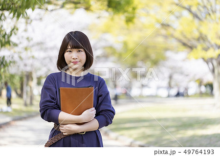 春の公園で書類を抱きかかえる学生の写真素材