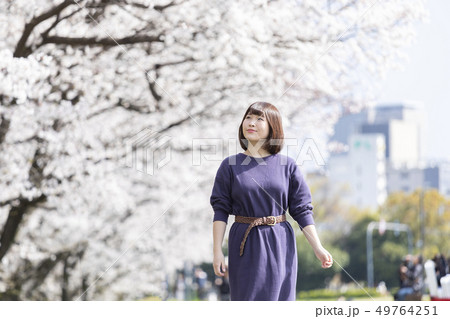 桜並木を散歩する女性 49764251